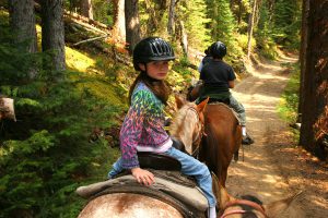 Young girl having fun horseback riding on mountain trail.